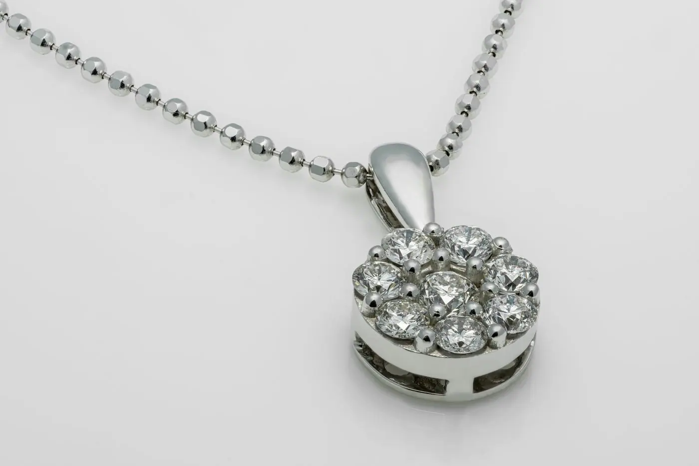 White-gold round diamond cluster pendant on a beaded chain, light gray background