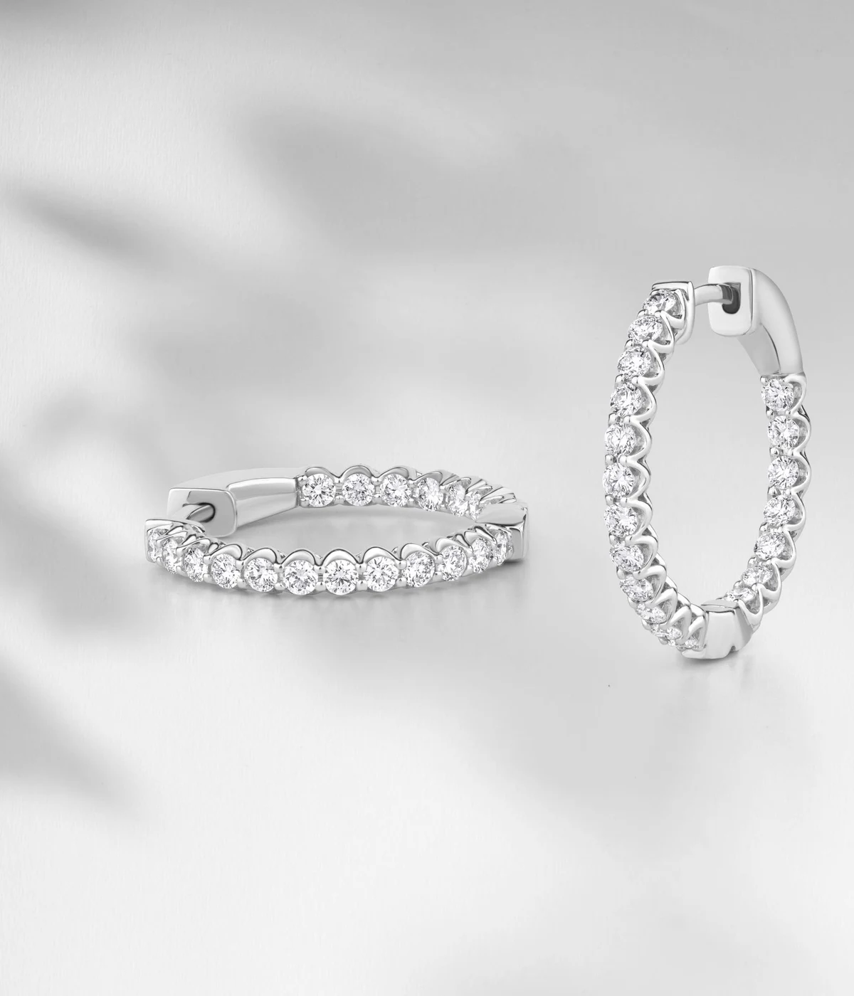 Pair of white-gold diamond hoop earrings on a light backdrop
