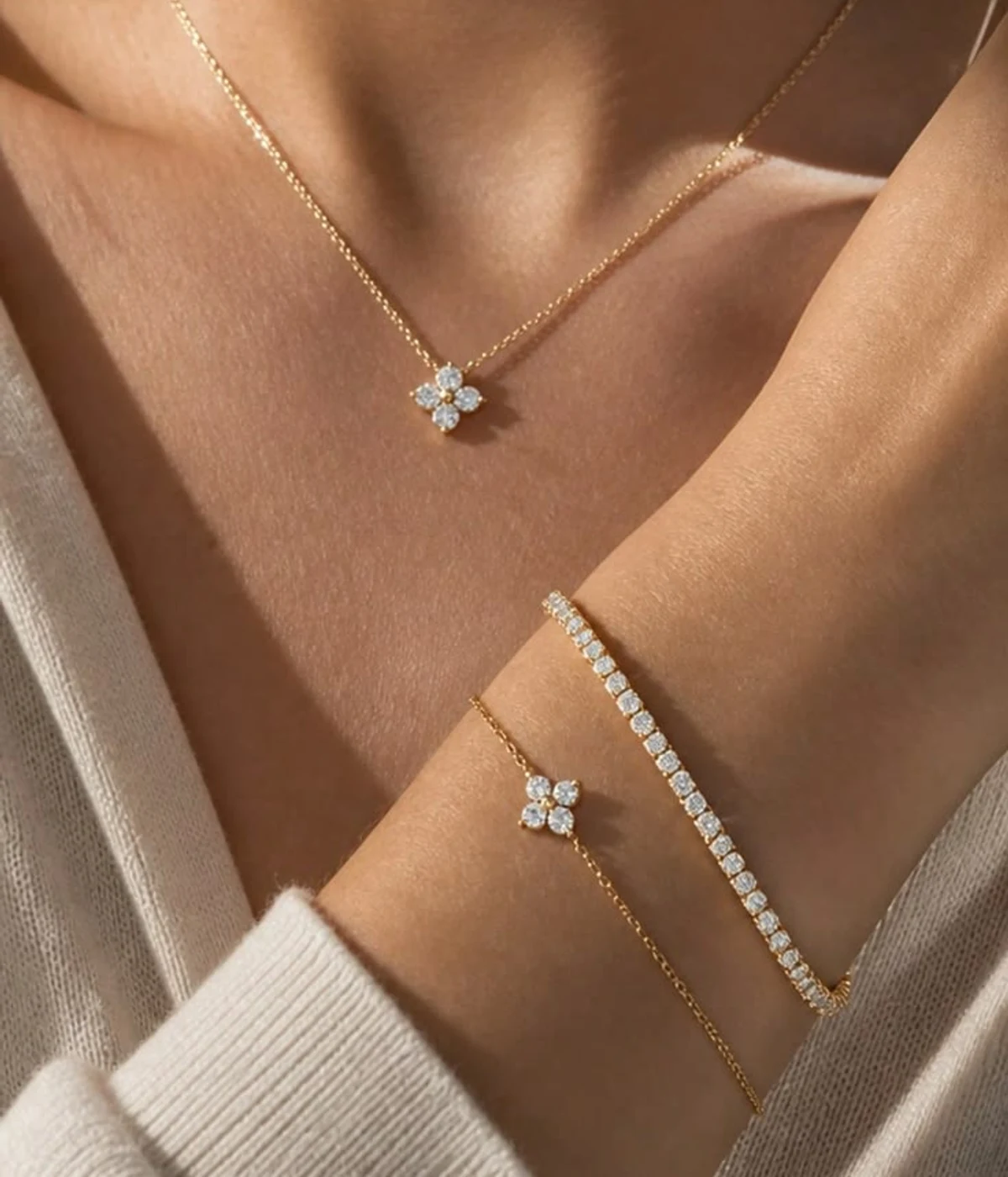 Diamond tennis bracelet layered with a clover chain bracelet and matching clover necklace