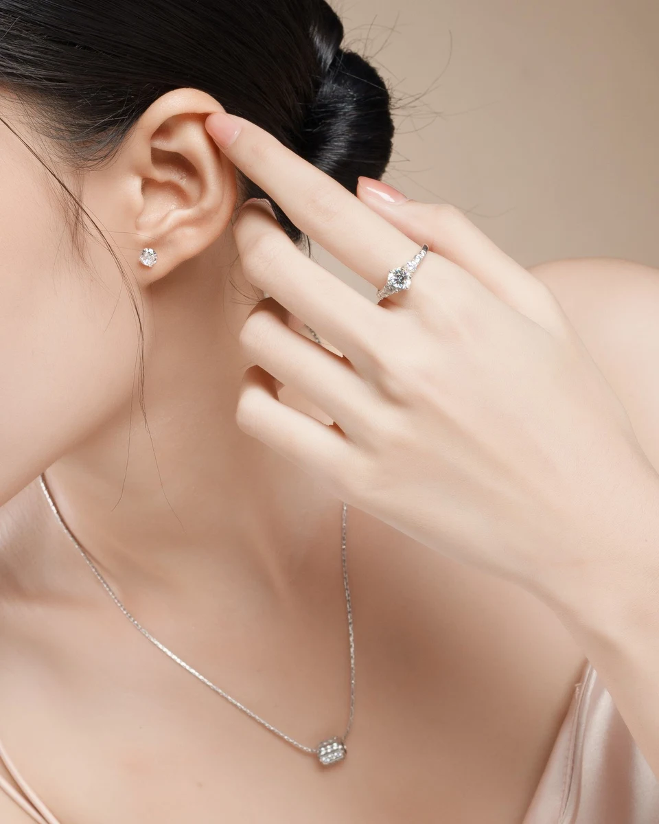 Solitaire diamond stud earring worn with a fine pendant and a diamond ring