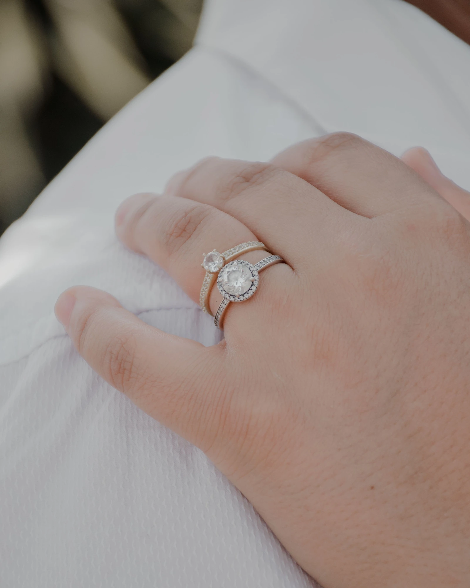 Custom diamond engagement rings worn on a hand with a soft white shirt