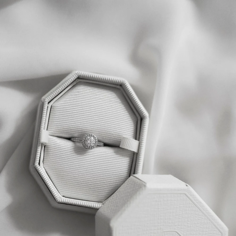 Halo diamond ring resting in an open white octagonal ring box