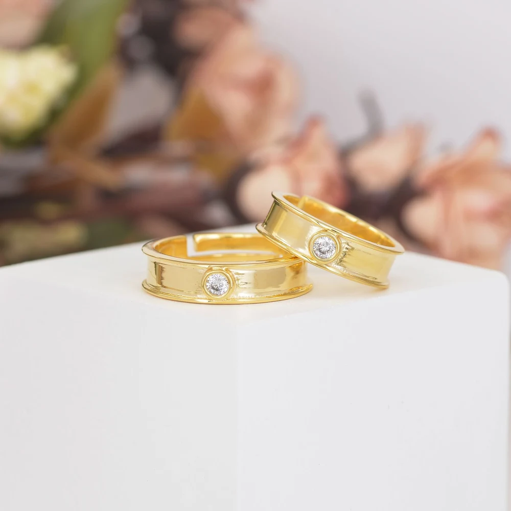 Two gold wedding bands set with diamonds on a white surface