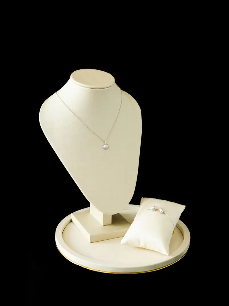 Diamond solitaire necklace and ring on a cream display bust