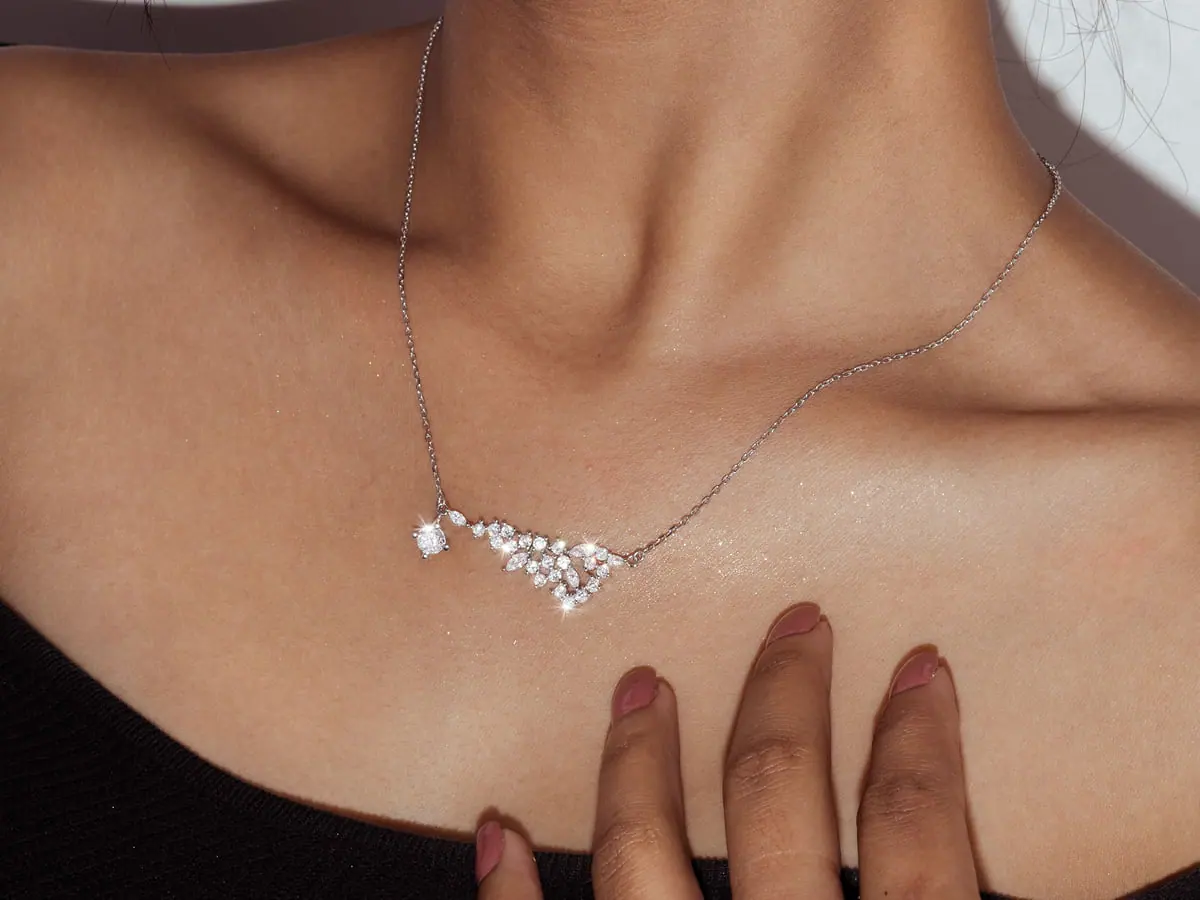 Model wearing a white-gold diamond cluster necklace at the collarbone