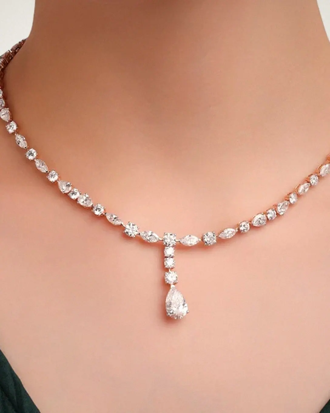 Neckline wearing a mixed-cut diamond riviera necklace with a pear diamond drop
