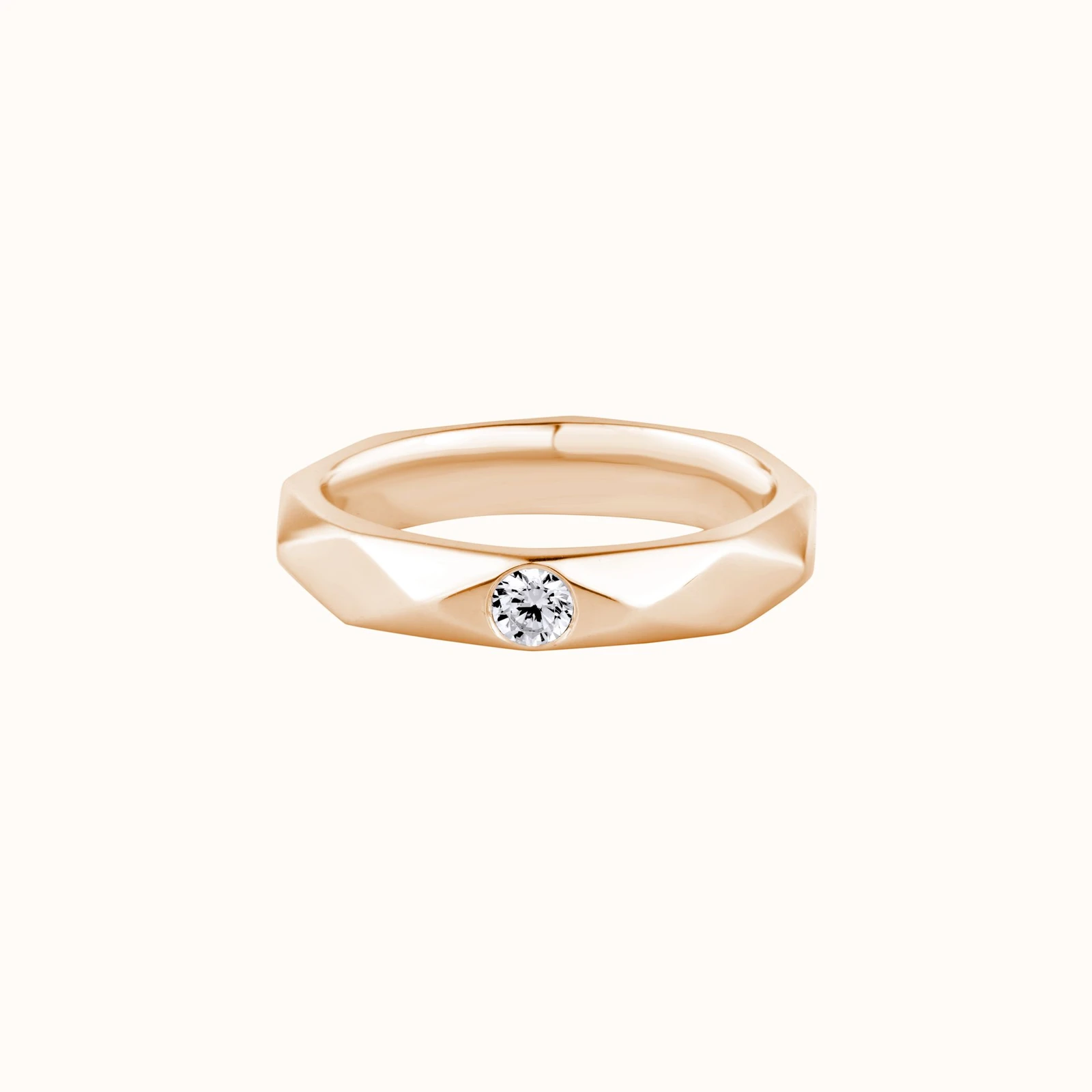 Faceted gold band set with a single round diamond on a plain white background