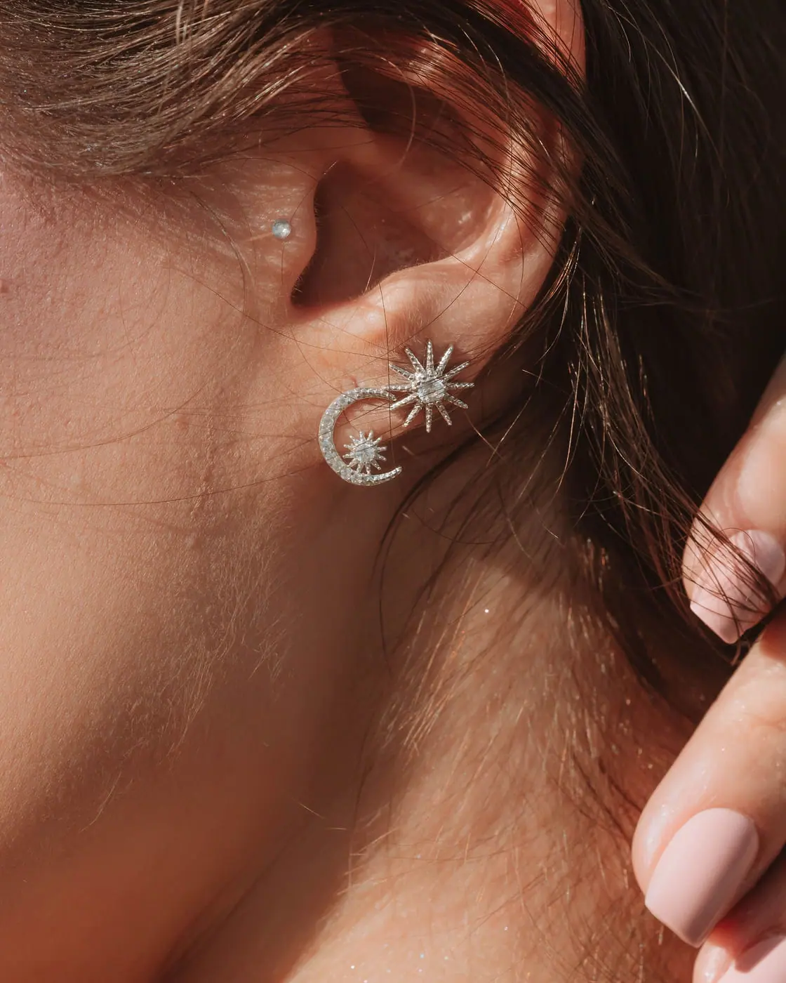 Ear wearing a white-gold pavé diamond crescent moon and star stud