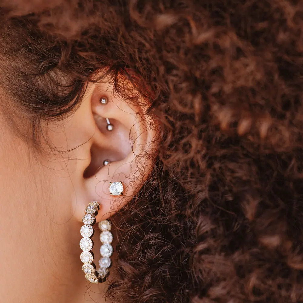 Ear wearing a white-gold diamond hoop earring and a diamond stud