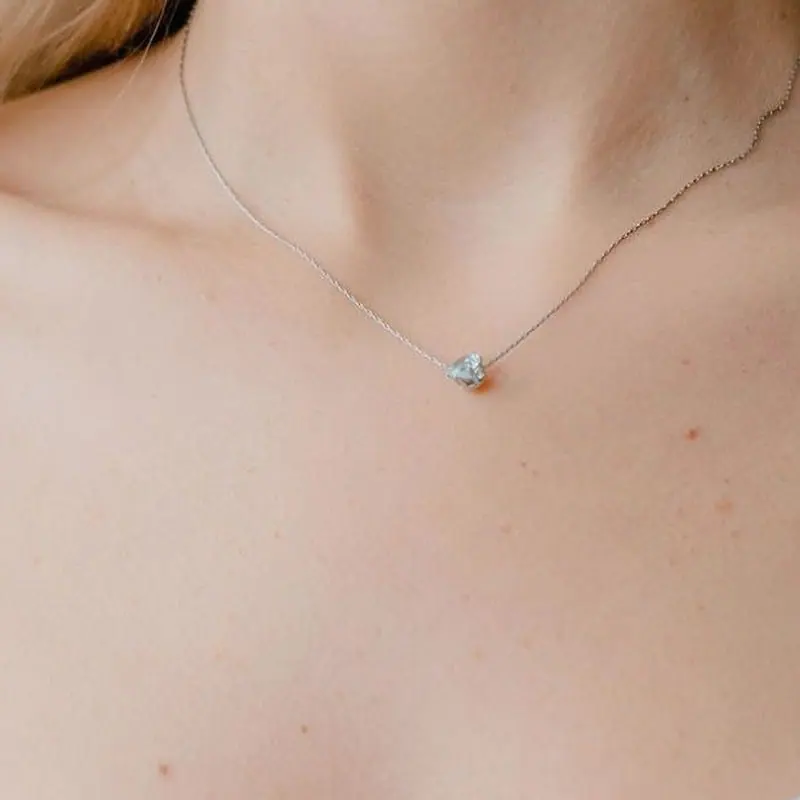 Petite diamond solitaire on a fine white-gold chain at the collarbone