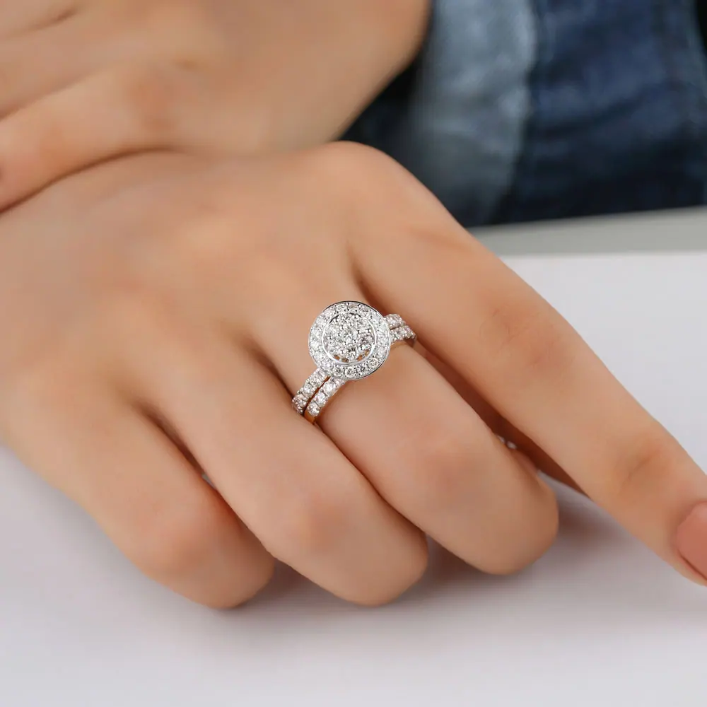 Diamond halo ring worn on a hand against a soft white backdrop