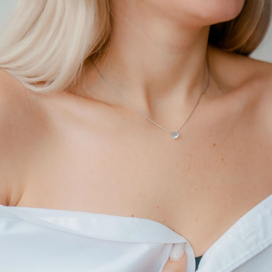 Solitaire diamond pendant on a fine white-gold chain worn with a white shirt