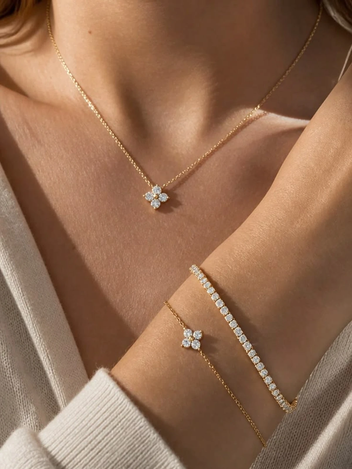 Diamond tennis bracelet layered with a clover chain bracelet and matching clover necklace
