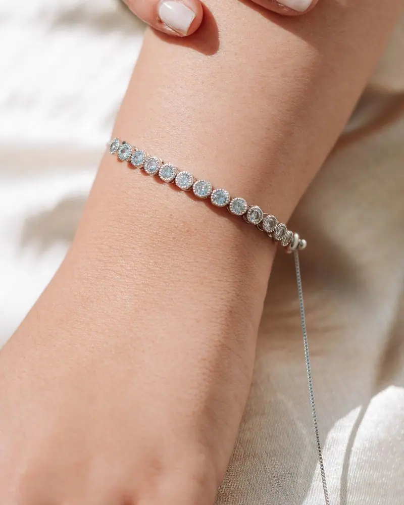 Woman’s wrist wearing a white-gold bezel diamond tennis bracelet