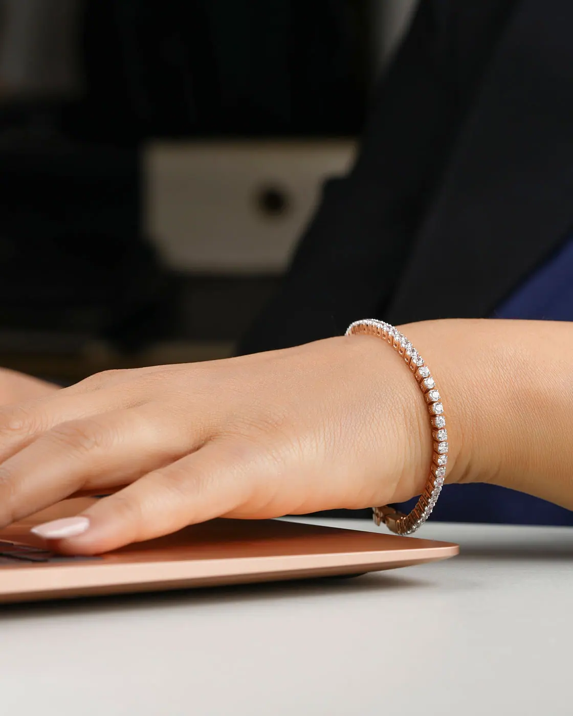 Hands typing on a laptop wearing a white-gold diamond tennis bracelet