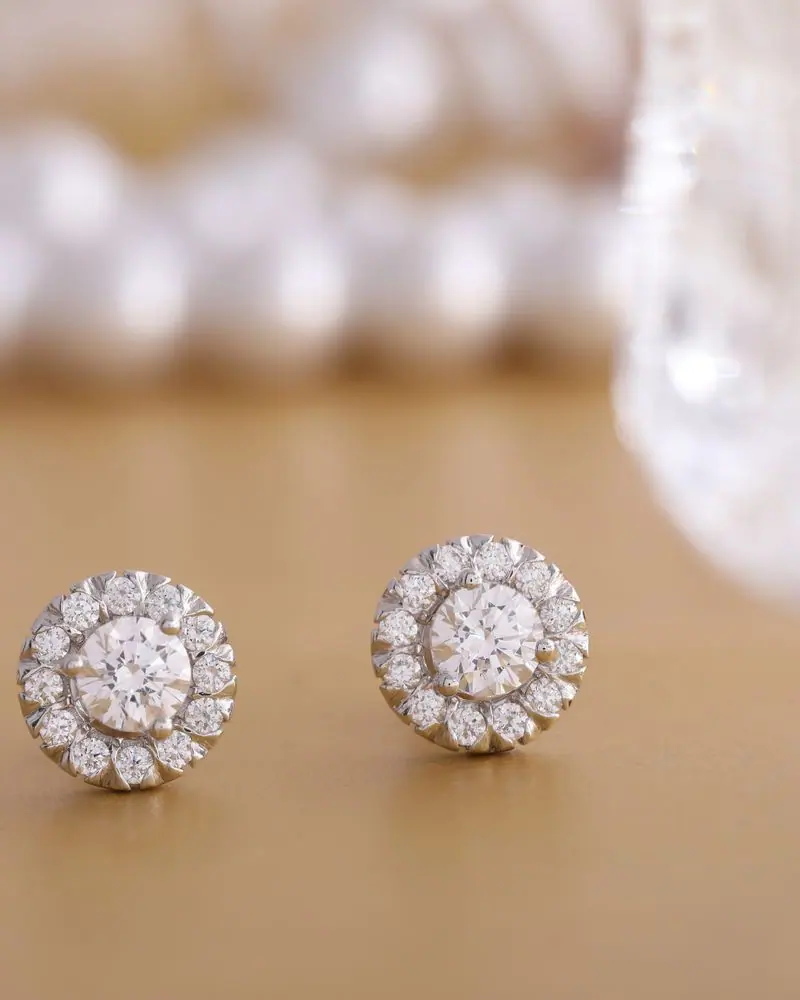 Round diamond cluster halo studs in white gold on beige