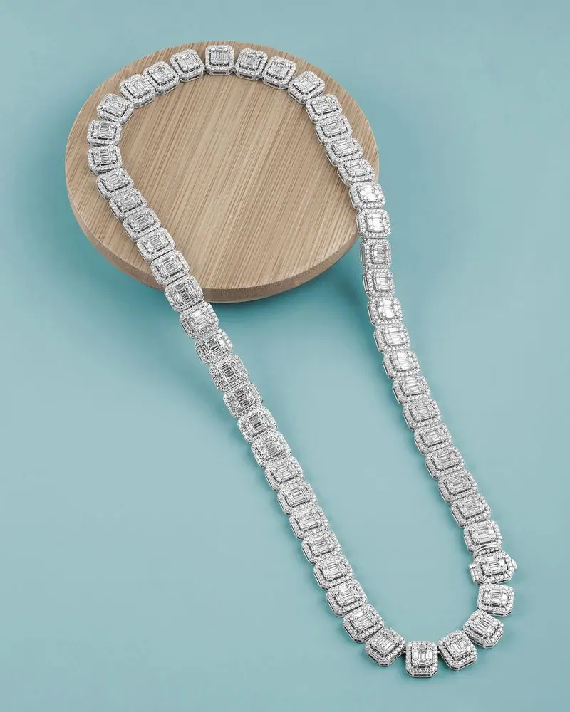 White-gold emerald-cut diamond tennis necklace draped over a wooden disc