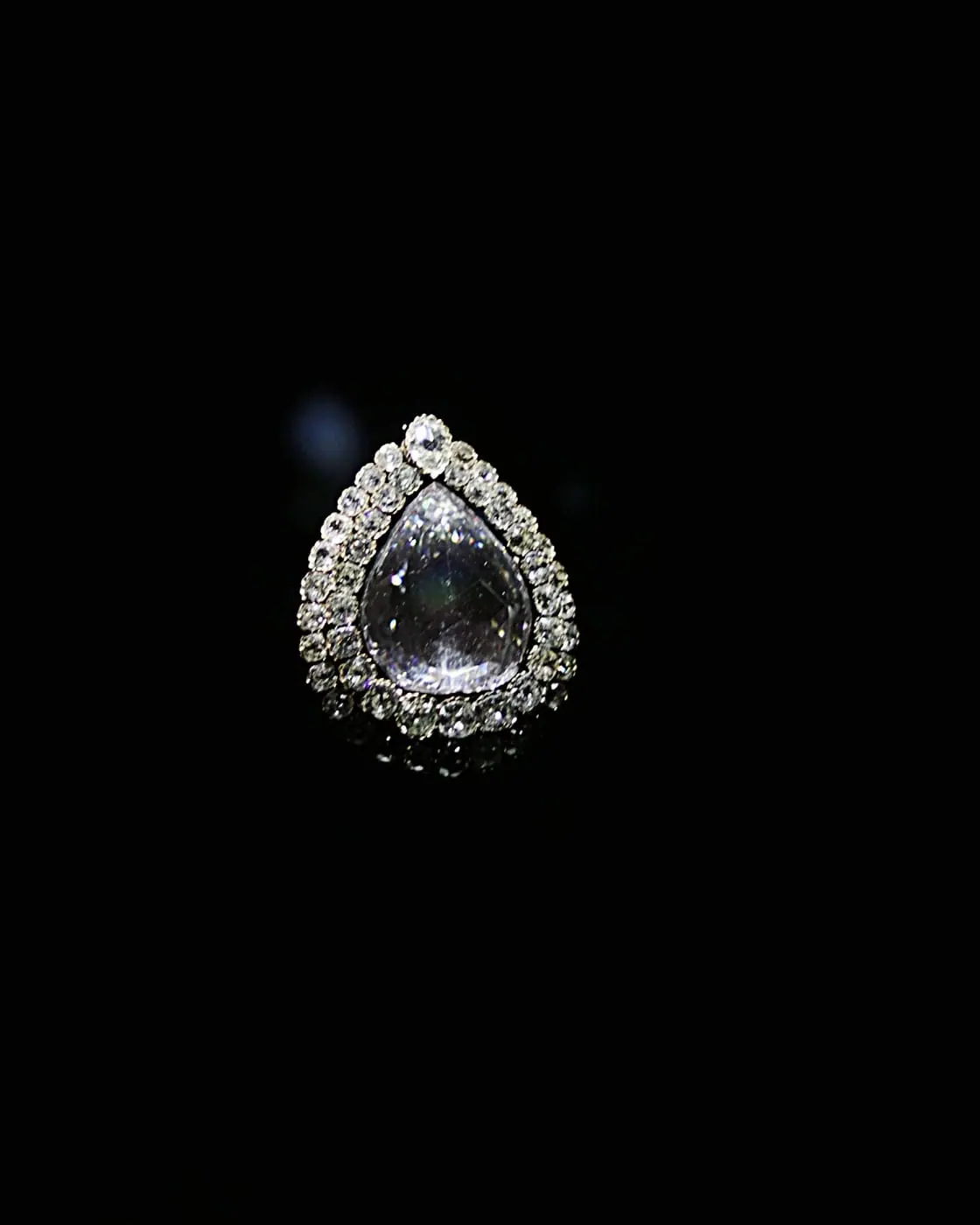 Pear-shaped diamond halo pendant glowing on black