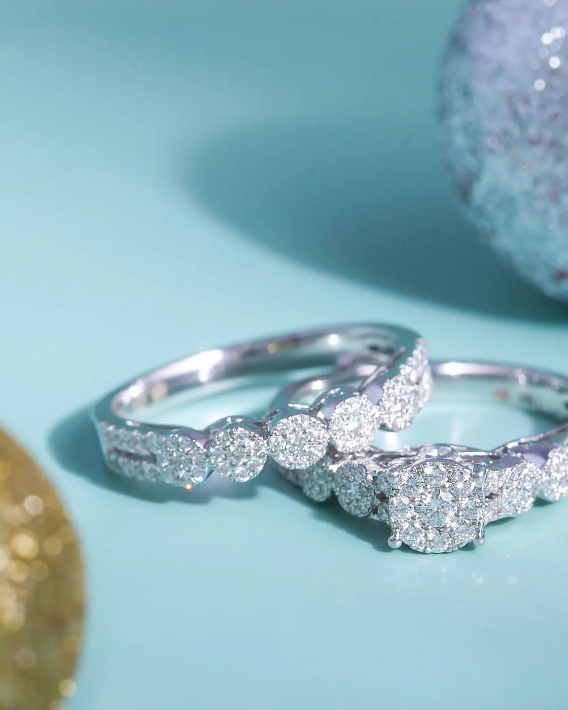 White-gold diamond cluster engagement ring and pavé band on teal