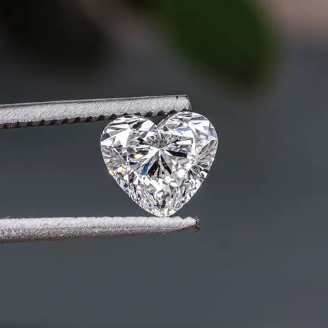 Heart-shaped diamond held in jeweler’s tweezers