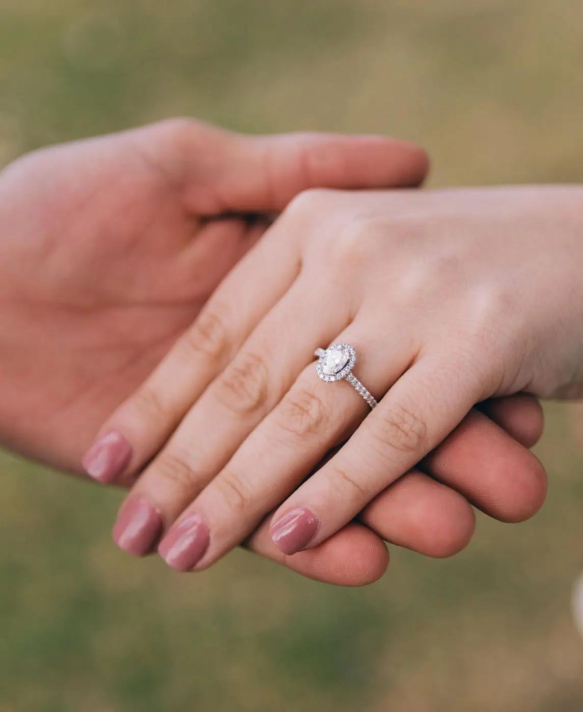 An oval diamond halo ring worn outdoors