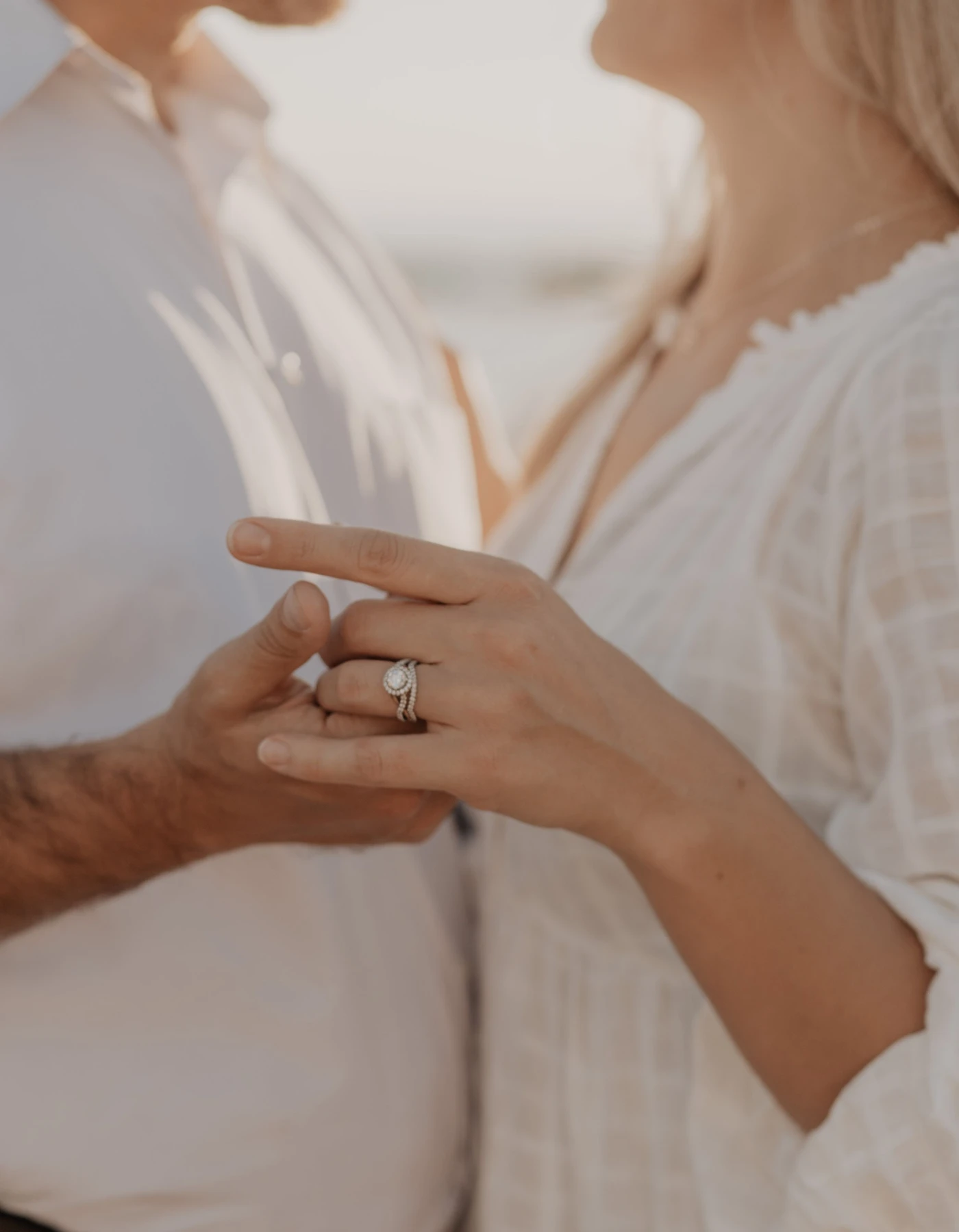 Couple’s hands, her diamond solitaire engagement ring in focus