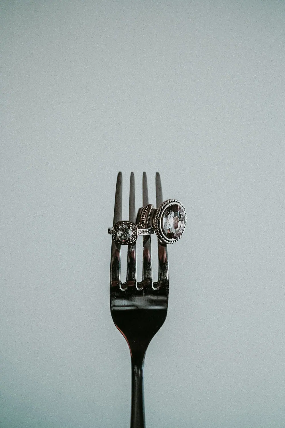 Diamond rings displayed on the tines of a silver fork