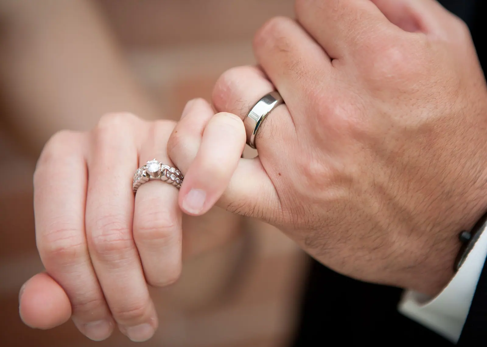 Couple holding hands with a diamond engagement ring